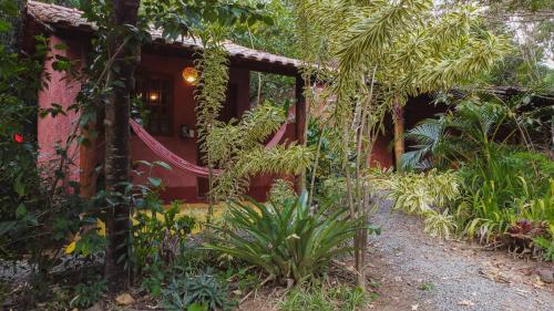 a garden in front of a red house at Pousada Donalu - Ótima Localização in Vale do Capao