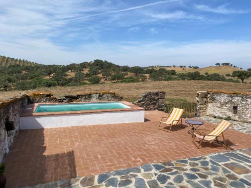 a patio with two chairs and a swimming pool at Country House and Estate - Herdade da Azinheira in Pavia