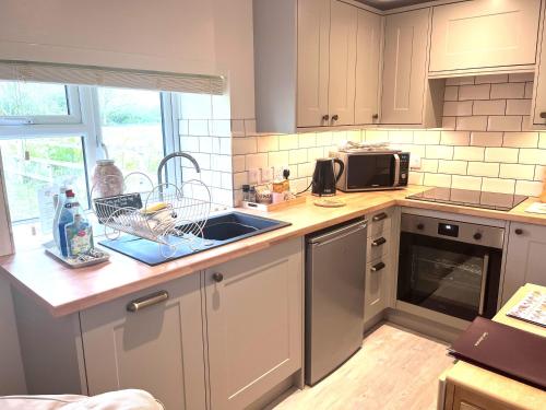 a kitchen with a sink and a microwave at Bridge Farm Holiday Cottages in Cow Honeybourne