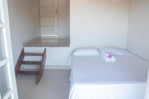 a small white room with a bed and a chair at Pousada Terra Nostra in Prado