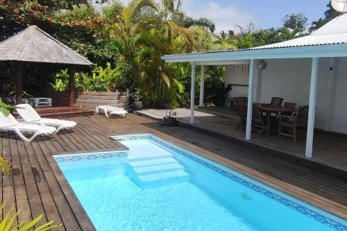une piscine avec une terrasse et une maison dans l'établissement Villa zen Bali piscine privée 3 chambres lotissement les hauts de la vallée d'or, à Saint-François