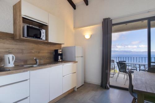 a kitchen with white cabinets and a view of the ocean at Residence Roc E Mare Cargèse in Cargèse