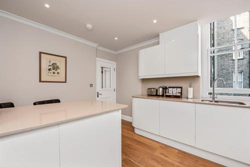 a white kitchen with white cabinets and a wooden floor at No1 The Mansions By Mansley in London