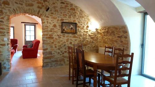 une salle à manger avec une table en bois et un mur en pierre dans l'établissement Mas Corsin, à Piolenc