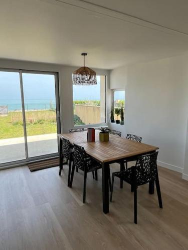une salle à manger avec une table et des chaises en bois dans l'établissement Superbe maison en front de mer, à Ver-sur-Mer