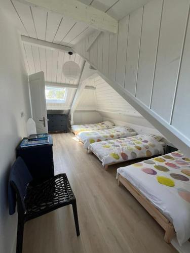 Cette chambre mansardée comprend 3 lits et une chaise. dans l'établissement Superbe maison en front de mer, à Ver-sur-Mer