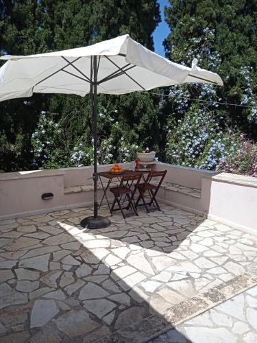 a table with an umbrella on a stone patio at Alegria house with gardens near portoheli in Kranidi