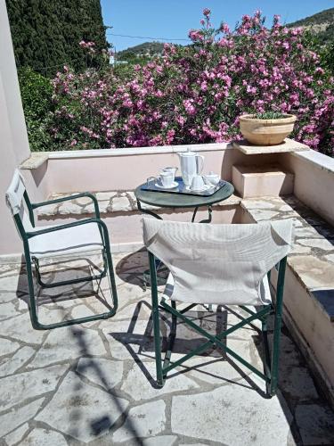 two chairs and a table on a patio with flowers at Alegria house with gardens near portoheli in Kranidi