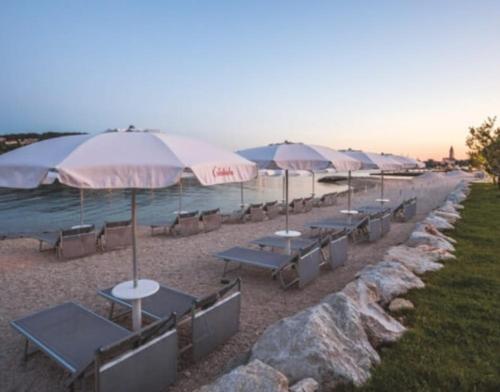 een rij tafels en parasols op een strand bij Dii Luxury Apartments in Trogir