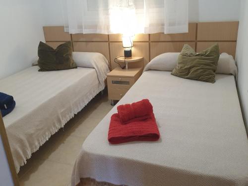een kamer met twee bedden met een rode handdoek erop bij Holidaytorremar-84-MED021 in El Borseral