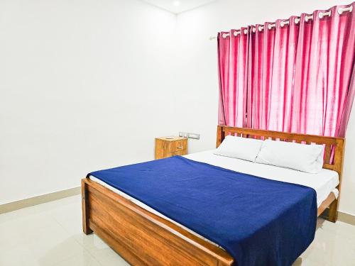 a bed with a blue blanket and a red curtain at Villa Espoir By Alchemy Homes in Ernakulam