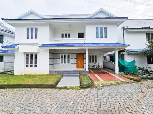 a white house with a driveway in front of it at Villa Espoir By Alchemy Homes in Ernakulam