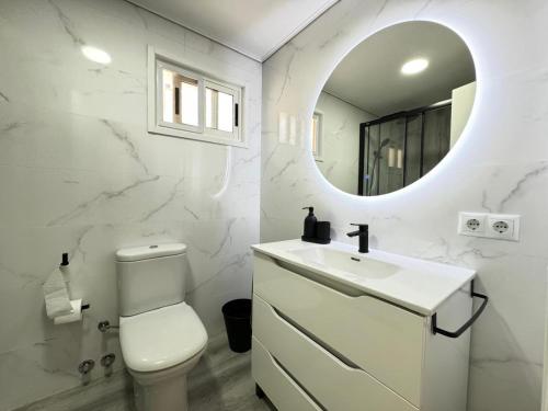 a white bathroom with a toilet and a mirror at La Casita Beach Garden By Sunset in Alicante