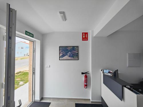 a hallway with a white wall with a fire hydrant at Pension Casa Pedro in Fisterra