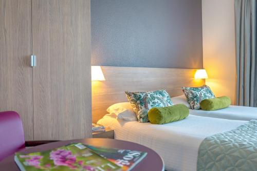 a hotel room with two beds and a table at Best Western Plus La Marina in Saint-Raphaël