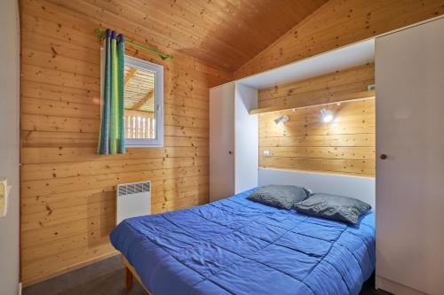 1 dormitorio con 1 cama azul en una cabaña de madera en Chalet 5 personnes 302, en Mens