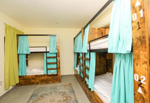 two bunk beds in a room with blue curtains at The Villa Hostel Abu Dhabi in Abu Dhabi