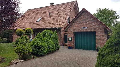 a brick house with a green garage at Ferienwohnung Kerstin in Strackholt in Großefehn 