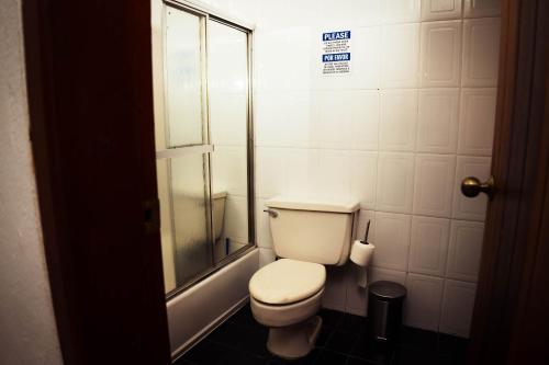a bathroom with a toilet and a glass shower at Residenciales H1 & H2 - Breakfast & Room Service - Airport close in Santiago de los Caballeros