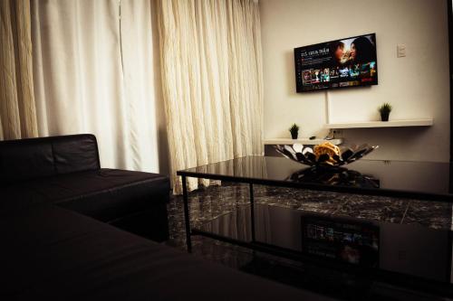a living room with a couch and a table and a television at Residenciales H1 & H2 - Breakfast & Room Service - Airport close in Santiago de los Caballeros