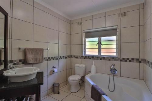 a bathroom with a tub and a toilet and a sink at #16 Illovo Views in Kingsburgh