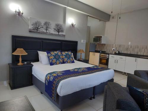 a bedroom with a large bed and a kitchen at Fairway Guest Lodge in Margate
