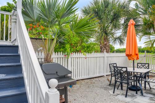 a patio with an orange umbrella and a table and chairs at Key West Home on Golf Course with Patio and Grill! in Key West