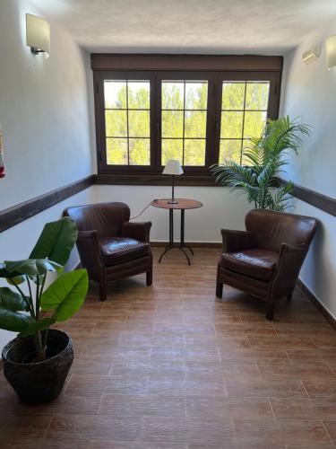 a living room with chairs and a table and windows at Hotel Rural Cazorla Posada del Cordobés in Cazorla