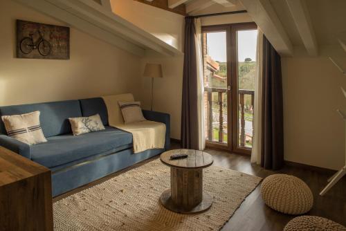 - un salon avec un canapé bleu et une table dans l'établissement Apartamentos Estela de Altamira, à Santillana del Mar