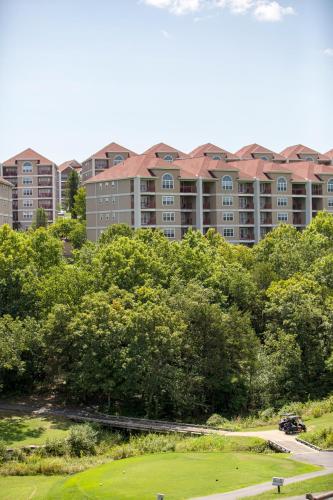 an apartment building in the background with trees and a golf course at Grand Crowne Resort by Capital Vacations in Branson