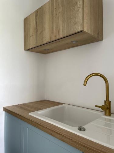 une cuisine avec un évier blanc et un meuble en bois dans l'établissement Les pins du Capri - Meublé de tourisme 3 étoiles, à La Grande Motte