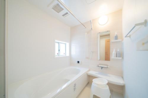 a white bathroom with a tub and a sink at Lawsoon in Uruma