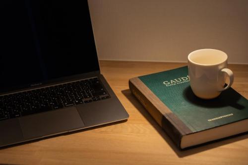 a coffee cup sitting on a book next to a laptop at Lawsoon in Uruma