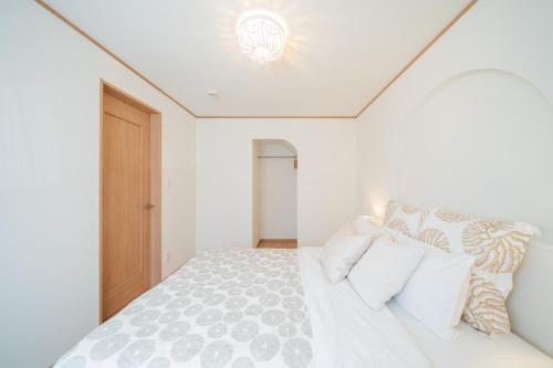 a white bedroom with a large white bed with pillows at Lawsoon in Uruma