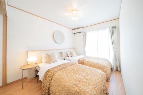 two beds in a white room with a window at Lawsoon in Uruma