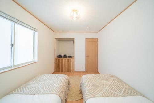two beds in a room with a window at Lawsoon in Uruma