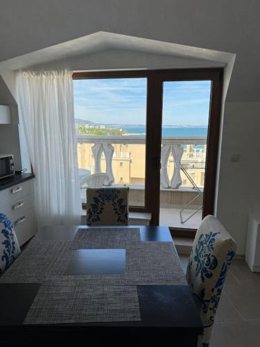 a dining room table with a view of a balcony at Апартамент с изглед към морето в Ла Мер in Golden Sands