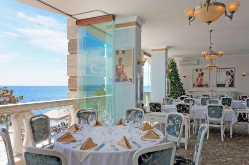 a dining room with white tables and chairs and the ocean at Апартамент с изглед към морето в Ла Мер in Golden Sands