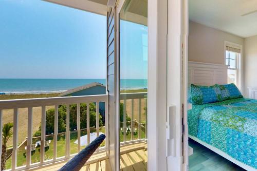 una camera da letto con balcone, letto e vista sull'oceano di Docs Boardwalk a Kure Beach