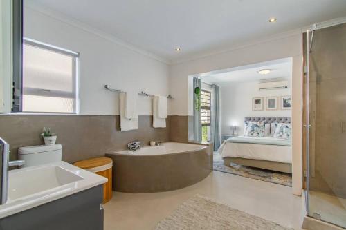 a bathroom with a bath tub and a bed at Chic, Cozy, Modern, Secure and Centrally Located in Cape Town