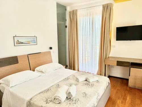 a bedroom with two beds with white sheets and a television at La Gaetana in Gaeta