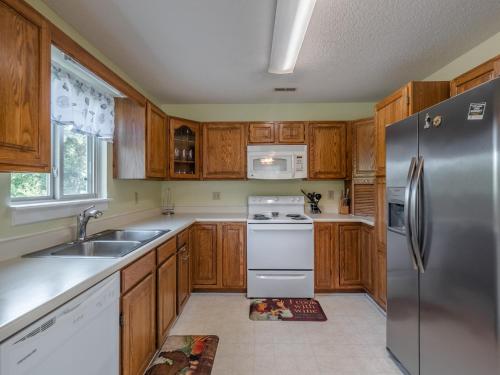 a kitchen with wooden cabinets and a stainless steel refrigerator at Just Another Day in Paradise in Surf City