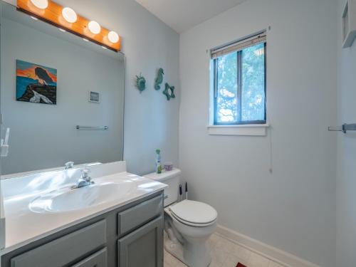 a bathroom with a sink and a toilet and a window at Just Another Day in Paradise in Surf City