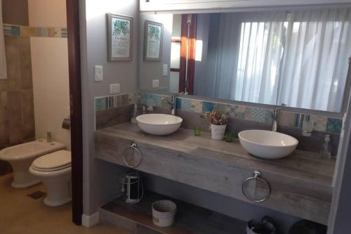 a bathroom with two sinks and a toilet and a mirror at CASA VIVE, EL MEJOR PAISAJE De SALTA in Salta