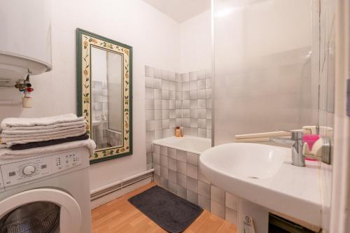 ein weißes Badezimmer mit einem Waschbecken und einer Waschmaschine in der Unterkunft Sarzeau centre - Le Cormoran in Sarzeau