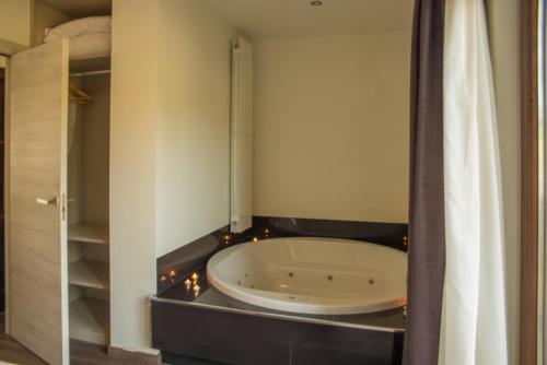 La salle de bains est pourvue d'une baignoire et de lumières. dans l'établissement Apartamentos Estela de Altamira, à Santillana del Mar