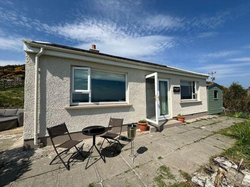a house with two chairs and a table in front of it at Stunning Rathlin cottage in Rathlin Island