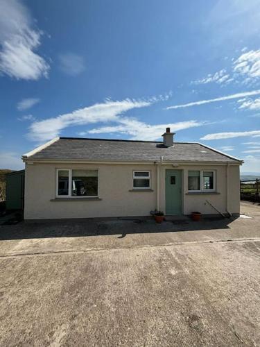 a white house with a green door in a driveway at Stunning Rathlin cottage in Rathlin Island