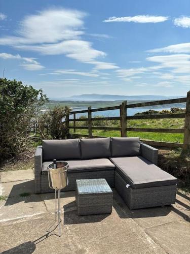a couch sitting on a patio with a view of the ocean at Stunning Rathlin cottage in Rathlin Island