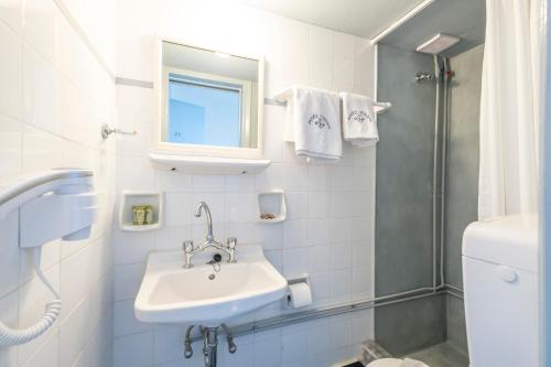 y baño blanco con lavabo y ducha. en Akroyiali - Guesthouse, en Yerolimin
